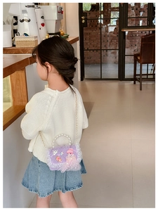 Detail der lila Spitzenhandtasche für Kinder mit Perlengriff in einem Café-Ambiente