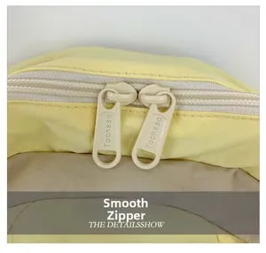Detail of dual plastic zippers with engraved logos on a light yellow kids backpack