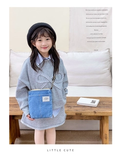 Detailed close-up of light blue denim kids crossbody bag with fashion label and zipper