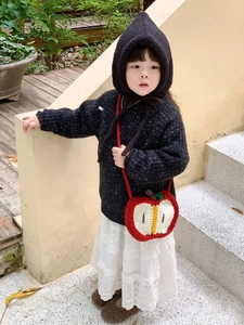 Close-up of handmade crochet apple-shaped crossbody bag on a child's fashion outfit
