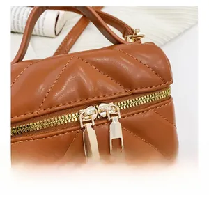 Detail of smooth gold double zippers and V-shaped quilted leather texture on girl purse