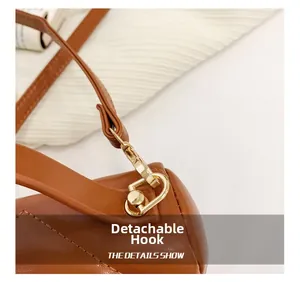 Close-up of detachable golden metal hook and quilted leather texture on brown kids bag