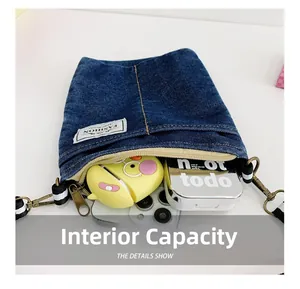 Detail view of denim crossbody bag showing internal capacity for phone and accessories