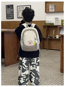 Rear view of a child wearing the minimalist cream and brown backpack in a cozy bookstore