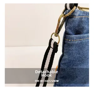 Detail of denim bag showing a detachable antique bronze hook and striped fabric strap