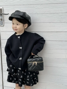 Close-up of girl's black quilted mini bag with gold zippers and metal chain strap