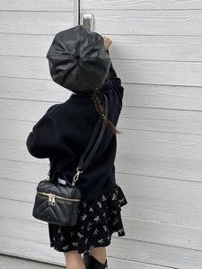 Detail of a black quilted mini chain bag paired with a stylish girl's fashion outfit
