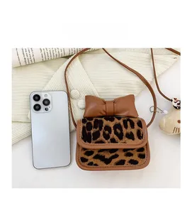 Mini leopard print crossbody bag with bow detail shown next to a smartphone for size reference