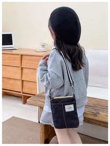 Detail of deep blue denim kids crossbody bag with adjustable striped strap and fashion label
