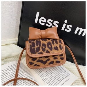 Close-up of leopard print toddler crossbody bag with large brown bow on vintage book