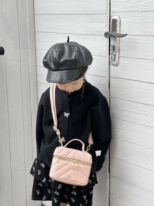 Close-up of pink quilted mini shoulder bag for kids with gold metal zippers and strap