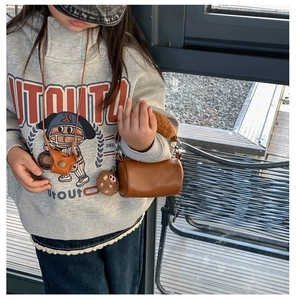 Brown plush cylindrical handbag for kids with a matching neck pouch shown on a child model