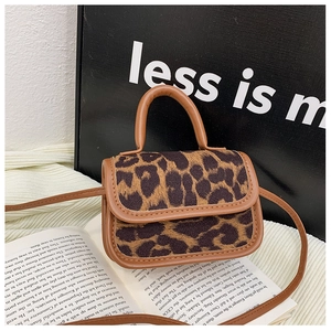 Detail of leopard print fabric and brown leather handle on a mini girls shoulder bag