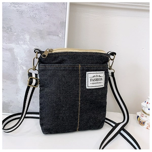 Detail of blue denim crossbody bag featuring contrast stitching and fashion woven label