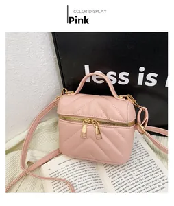 Detailed view of pink quilted mini vanity bag with gold zippers and top handle