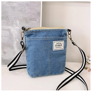 Detail view of denim crossbody bag with adjustable striped strap and metal hook
