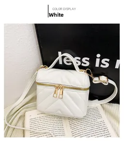 Detailed view of white quilted mini bag with V-shaped stitching and top handle
