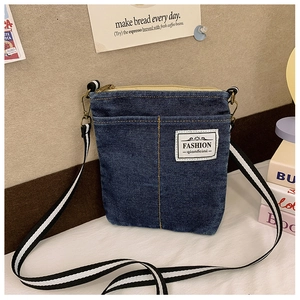 Detail of blue denim kids crossbody bag with fashion label and striped woven strap