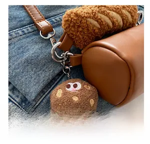 Detail of cute brown plush biscuit charm with silver metal clasp on leather bag