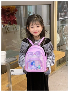 Detail of girls' purple backpack featuring a large bow and sequin mermaid glitter pocket