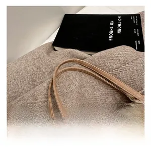 Detailed close-up of khaki knitted texture and fringe detail with leather handle