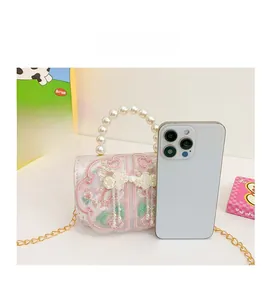 Detail view of pink embroidered girls bag with pearl handle and metal chain for scale