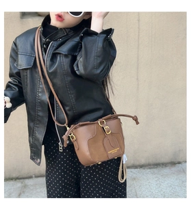 Detail of child's brown leather bucket bag showing mixed textures and metal buckle