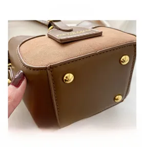 Close-up of brown bucket bag bottom with gold metal feet and premium stitching