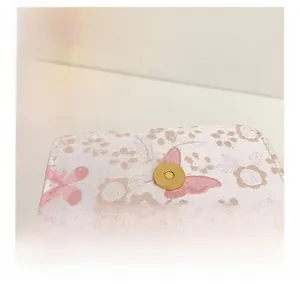 Detail showing white floral jacquard fabric with a gold circular magnetic buckle closure