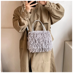 Detail shot of light grey plush handbag with long faux fur and slim white handle