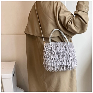 Detail view of purple faux fur fringe handbag with shoulder strap on a trench coat
