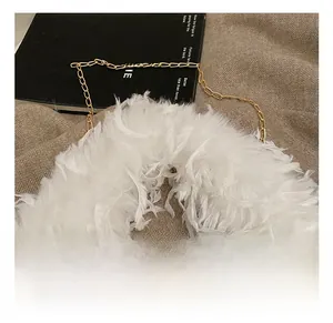 Détail d'un sac à main en plumes blanches avec chaîne dorée et texture douce