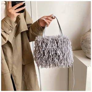 Detail of grey faux fur crossbody bag with long fringes paired with a khaki trench coat