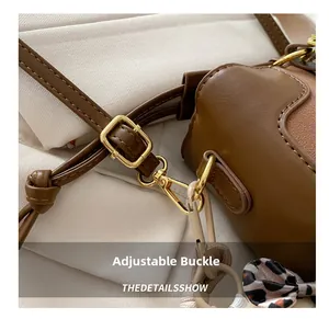 Detail of adjustable gold buckle and brown leather strap on child bucket bag