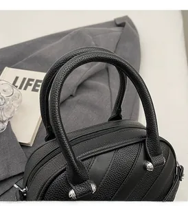 Dettaglio borsa in pelle nera con borchie argentate e manici robusti e resistenti