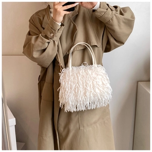 Close-up of white plush handbag featuring elegant gold chain strap and fluffy faux fur texture