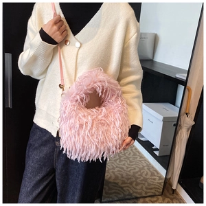 Gros plan d'un sac à bandoulière en fausse fourrure rose avec chaîne porté par un modèle