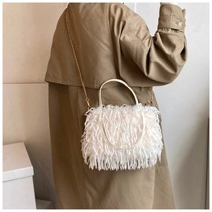 White faux fur crossbody bag with golden chain strap shown on khaki trench coat