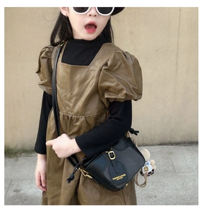 Detail of girls' black leather bucket bag with plush charm and fashion typography
