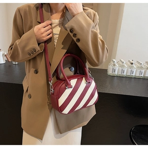 Dettaglio di una borsa a tracolla a righe rosse e bianche con trama in pelle martellata