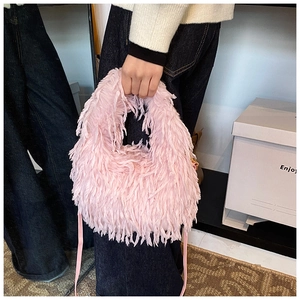 Détail de la texture en fausse fourrure rose et de la fine bandoulière sur le sac chic