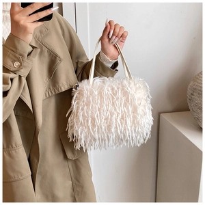 Close-up of white plush crossbody bag with fringe texture and smooth leather handle