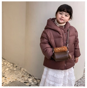 Detail of a brown plush cylindrical bag with cute bread accessory on a model