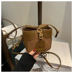 Detail of the brown patchwork bucket bag with magnetic clasp and gold-tone hardware buckle