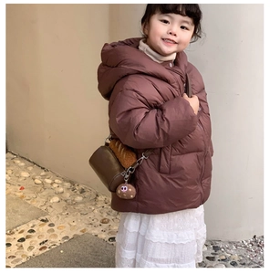 Detail of a plush brown cylinder handbag styled with a children's winter puffer coat
