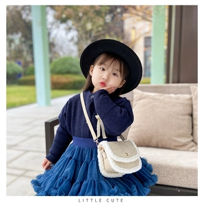 Little girl in elegant navy cardigan and mesh skirt with beige plush crossbody bag