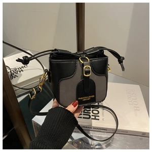 Detail of a mini two-tone bucket bag for girls with gold buckle and fashion leather text