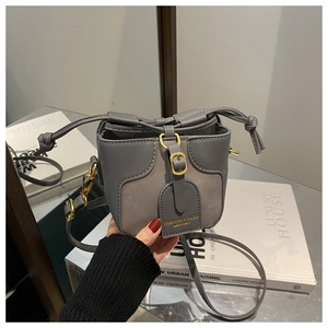 Detail of grey mini bucket bag showing leather texture, drawstring and gold buckle