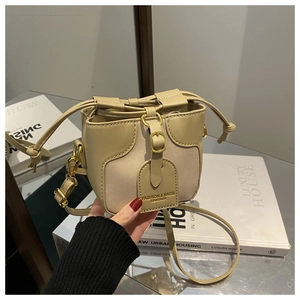 Detail view of contrast color bucket bag with drawstring closure and metal buckle