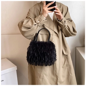 Close-up of black fuzzy plush handbag with fine gold chain and sleek top handle